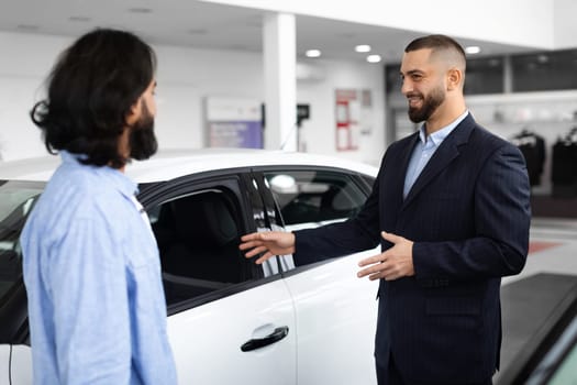 Young car salesman making deal with customer at the dealership