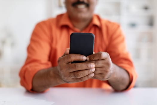 Cropped of eastern man sitting at table, using cell phone