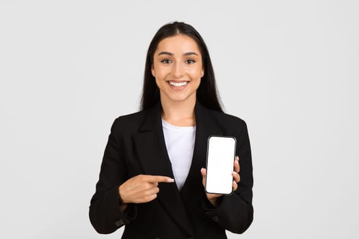Cheerful young businesswoman presenting smartphone with blank screen