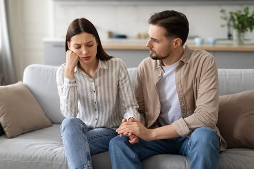 Concerned young man comforting upset woman on couch