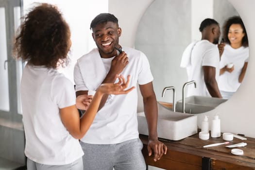 black couple talking and laughing while husband shaving in bathroom
