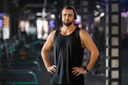 Portrait Of Handsome Young Muscular Man In Headphones Posing In Gym