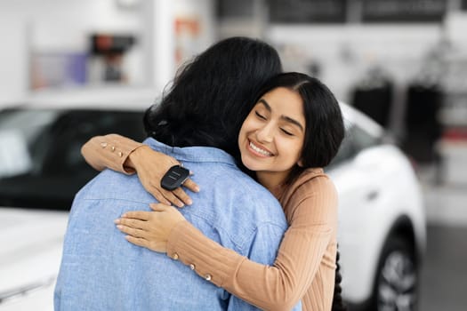 Happy young indian woman with car key hugging her husband