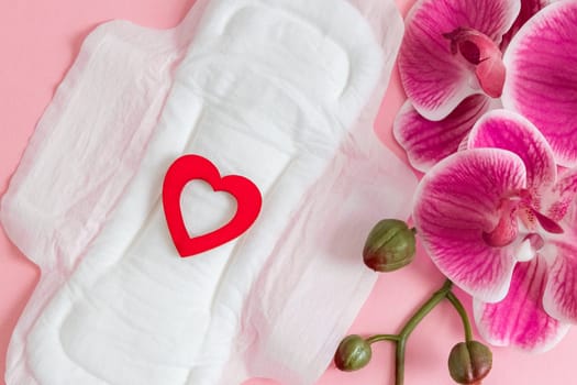 Women's sanitary pad with red heart and orchid on a pink background.