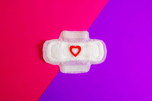 Women's sanitary pad with a red heart on a bright pink background.
