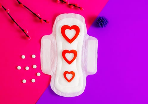 Women's sanitary pad with red hearts, pills, virus ball and willow branches on bright pink.