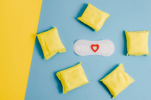 Women's sanitary pads with a red heart on a yellow-blue background.