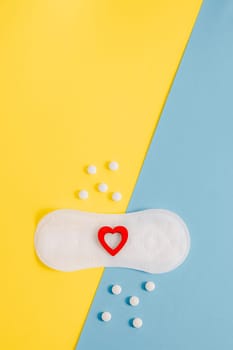 Women's sanitary pads with a red heart and pills on a yellow-blue background.