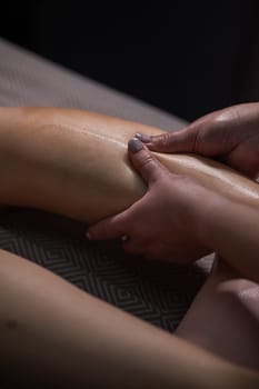 Close-up of a woman's leg massage in a salon. Vertical photo.