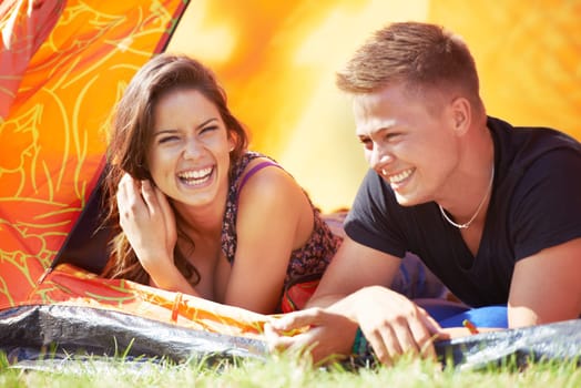 Happy couple, tent and laughing for funny joke, humor or bonding together at outdoor campsite. Face of young man and woman with smile enjoying fun holiday weekend, vacation and camping on green grass