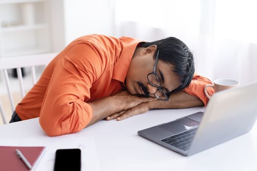 Tired middle aged indian man sleeping at working place