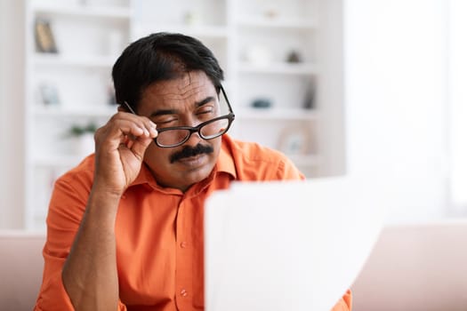 Desperate mature indian man getting bad shocking news from paper