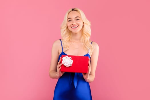 Smiling woman in blue holding a red gift, content and happy