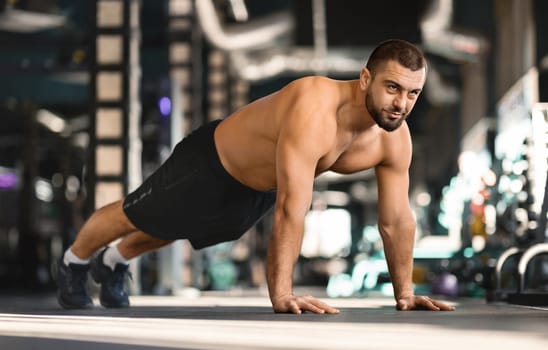 Focused man doing mid-push-up exercise while training at gym