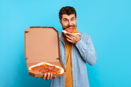 man enjoys slice of pizza holding carton delivery box, studio