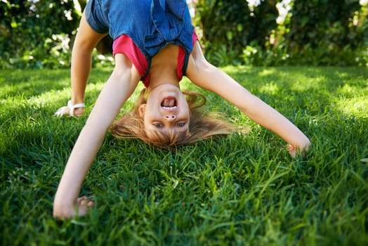 Child, back and bend or bridge or outdoor play in summer or flexibility game or practice, fun or backyard. Kid, face and excited or gymnastics stretching on grass lawn in London park, happy or garden