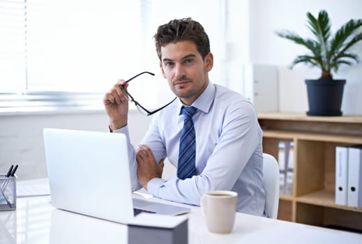 Portrait, office and businessman in glasses with laptop for market research at startup with coffee. Confidence, pride and business analyst at desk with computer, opportunity and internet technology.