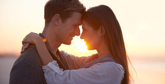 Couple, forehead touch on beach and sunset, nature and travel with bonding for love and commitment outdoor. People with support, trust and hug with adventure together for honeymoon or anniversary