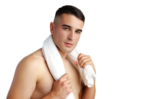 Young smiling man with towel on shoulders posing at camera on white background