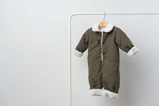 Baby gray quilted winter overalls on hanger against white wall