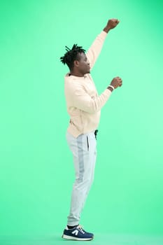 A man, full-length, on a green background, dancing