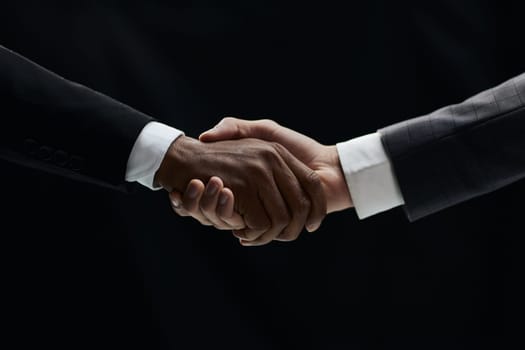African man's hand shaking white man's hand on black background