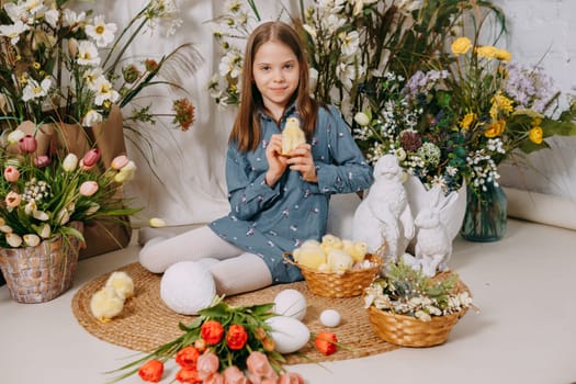 Two girls in a beautiful Easter photo zone with flowers, eggs, chickens and Easter bunnies. Happy Easter holiday.