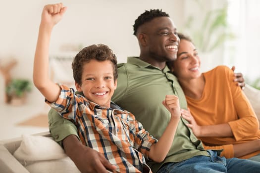 Happy boy gesturing yes while sitting with diverse parents indoor
