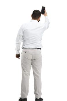 A man, full-length, on a white background, waving his phone