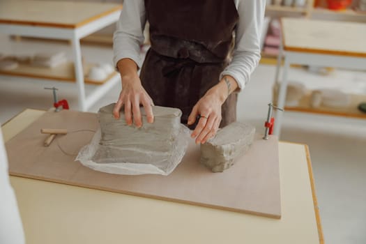 Close up of ceramist woman wearing apron is preparing clay to make pottery pieces in her studio