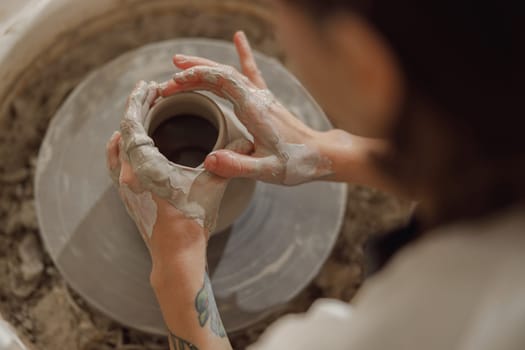 Close up of artisan's hands shaping clay bowl in pottery studio. Pottery art and creativity