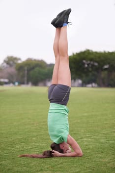 Headstand, sport and woman with fitness in a park with balance for wellness and health. Training, workout and outdoor on a field with exercise on a lawn with pilates and strong core practice