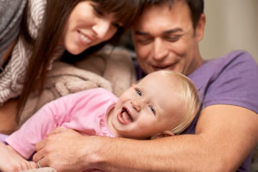 Love, hug and baby with parents in a house for playing, tickle or games while bonding in laughter. Happy family, face and kid with funny people in living room with support, trust or child development