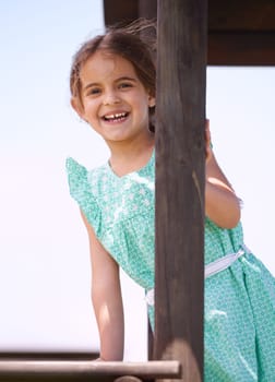 Portrait, smile and child at playground outdoor in summer for fun on vacation with cute, adorable and innocent girl. Playing, happy and kid at jungle gym, funny and laughing for joy alone in Spain