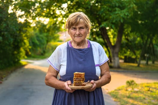 An elderly woman holds honey in her hands, selective focus.