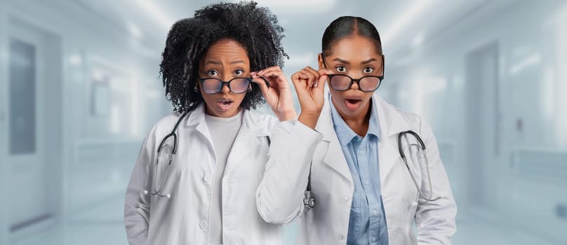 Two surprised female doctors in lab coats are adjusting their glasses in a hospital