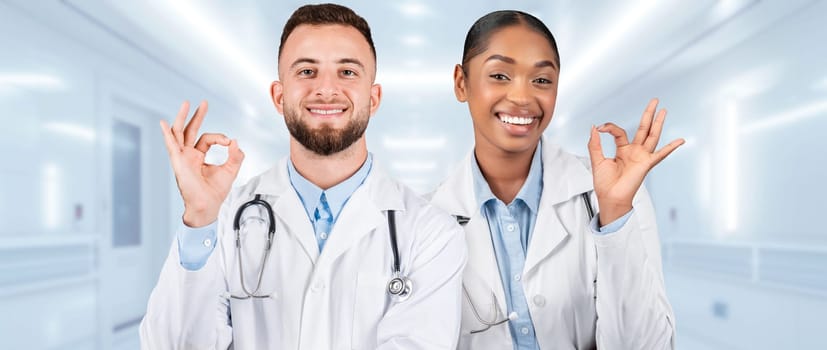 Smiling male and female medical professionals in white lab coats making okay