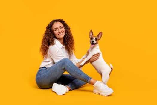 Smiling woman with her Jack Russell on bright yellow backdrop