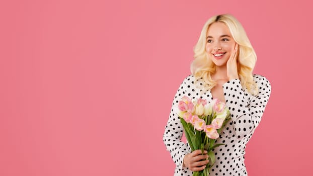 Smiling young woman with tulips against pink backdrop, free space