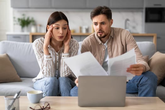 Worried spouses reviewing documents with laptop on the table