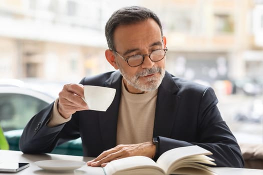 Mature man reading a book with coffee in a contemplative moment