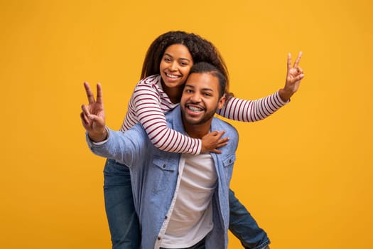Romantic black couple having fun together, showing V-sign gesture