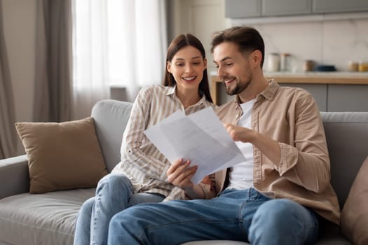 Spouses reviewing documents together on sofa