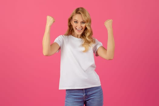 Portrait of joyful blonde lady gesturing yes over pink background