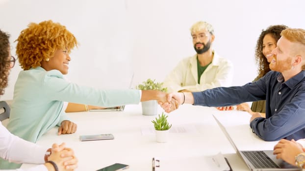 Business people handshaking sitting on a table with multi-ethnic coworkers