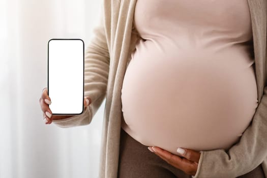 Cropped of pregnant black woman showing blank smartphone screen