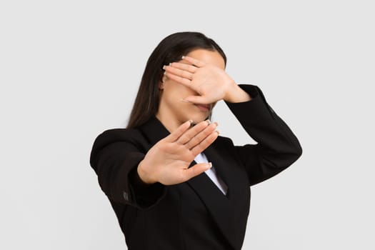 Businesswoman gesturing stop with her hand, covering face