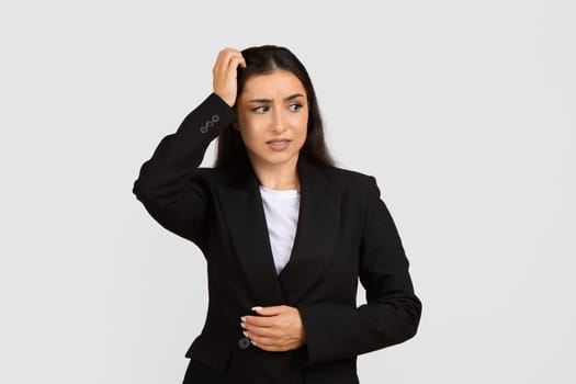 Confused businesswoman scratching her head, puzzled
