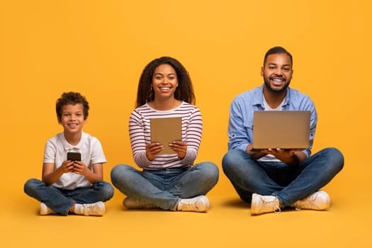 Modern black family with preteen son using different tech devices