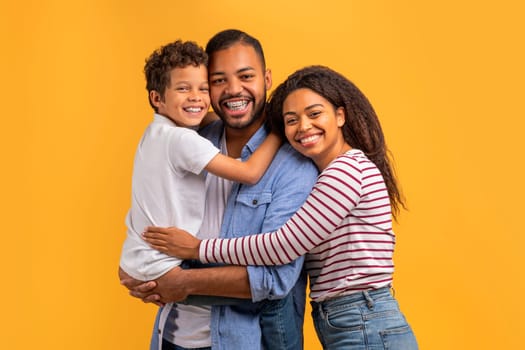 Heartwarming family portrait with black preteen boy cuddling with parents